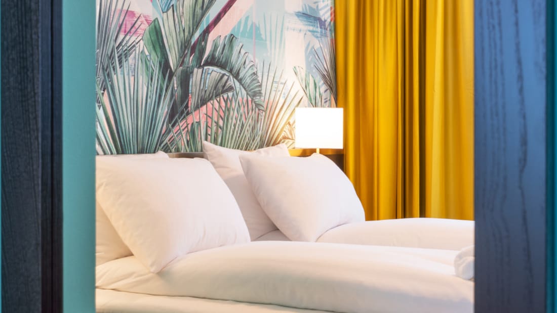 Dobbeltseng med tapet med jungleblade i suite på Thon Hotel Storo i Oslo