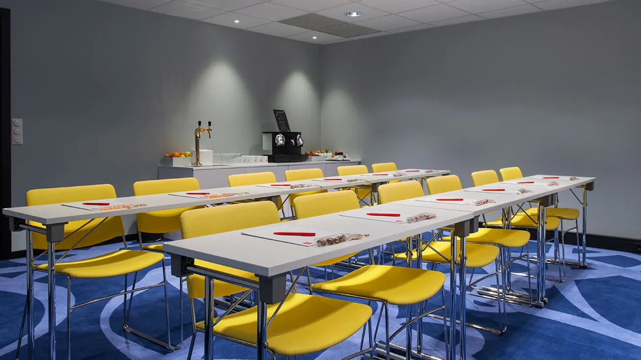 Conference meeting room, two long tables, eight seats, notepads, snacks and coffee in the background