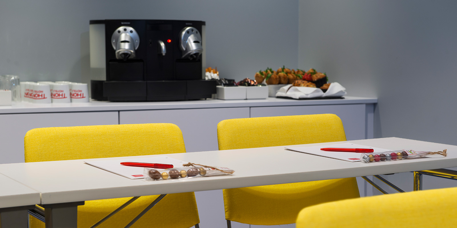 konferens mötesrum bord och stolar, anteckningsblock, kaffe och snacks i bakgrunden