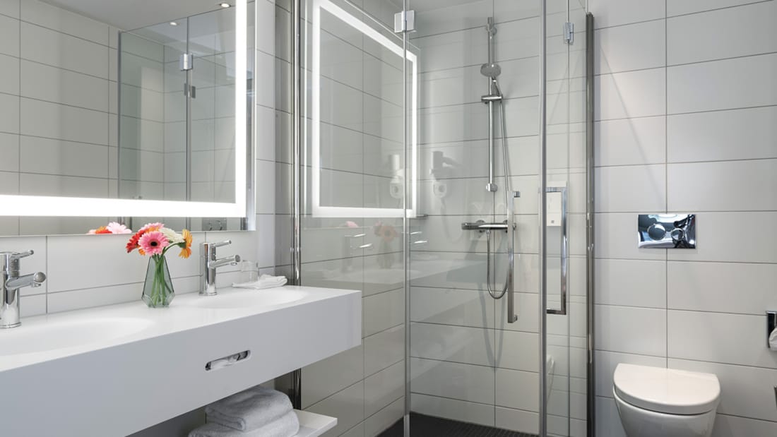 business room badeværelse med oplyst spejl, elegant servante, bruser og badekar