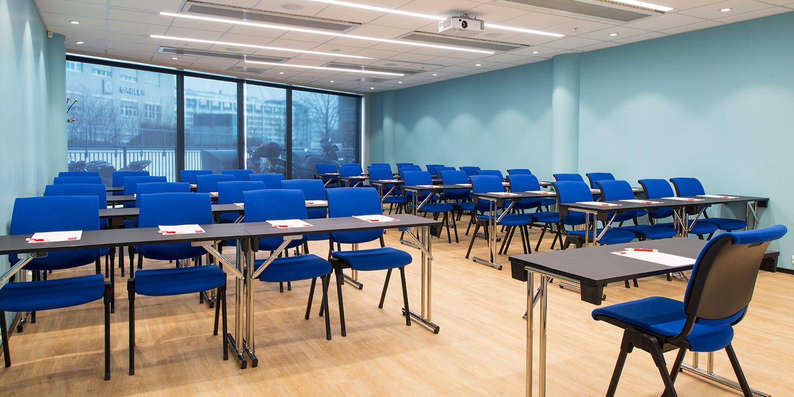 konferensrum holmenkollen, klassrumsmöblering, 40 platser, stolsrader med fyra stolar i varje rad, fönster i rummets bakre del, ledarstol längst fram