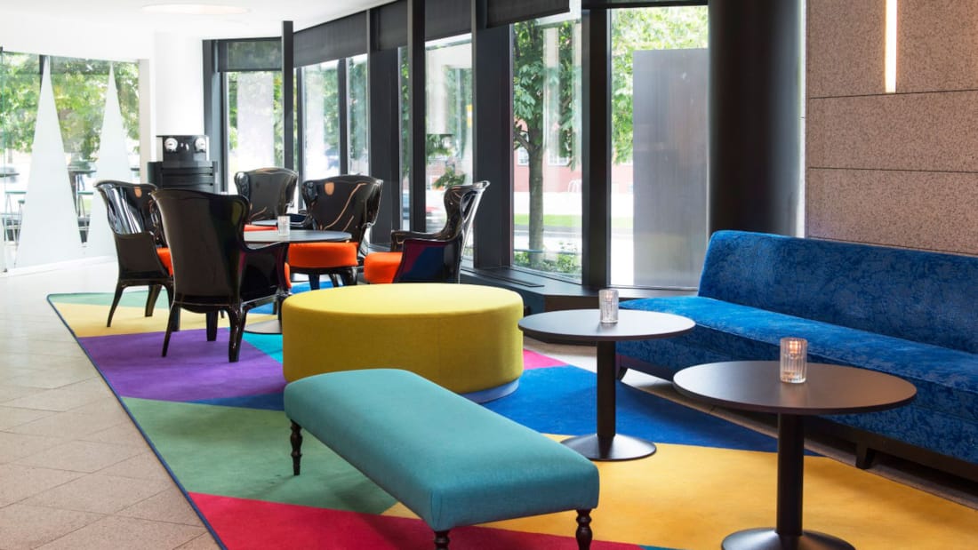 lobbyområde med sofa, siddepladser og caféborde ved indgangsparti, farverigt