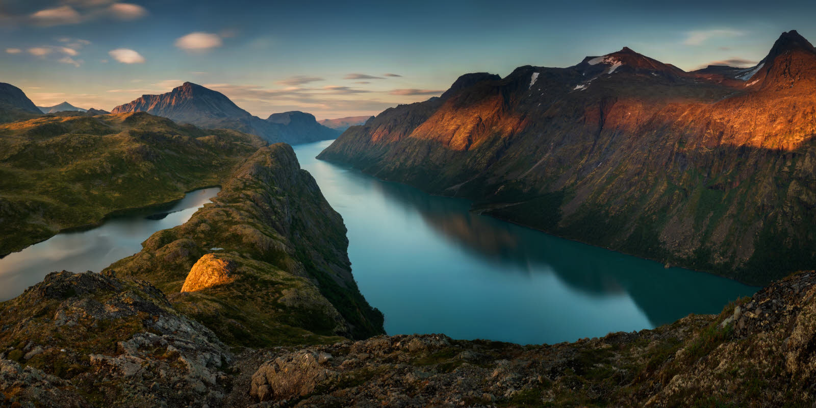 Vakkert bilde av solnedgang over fjell og vann.