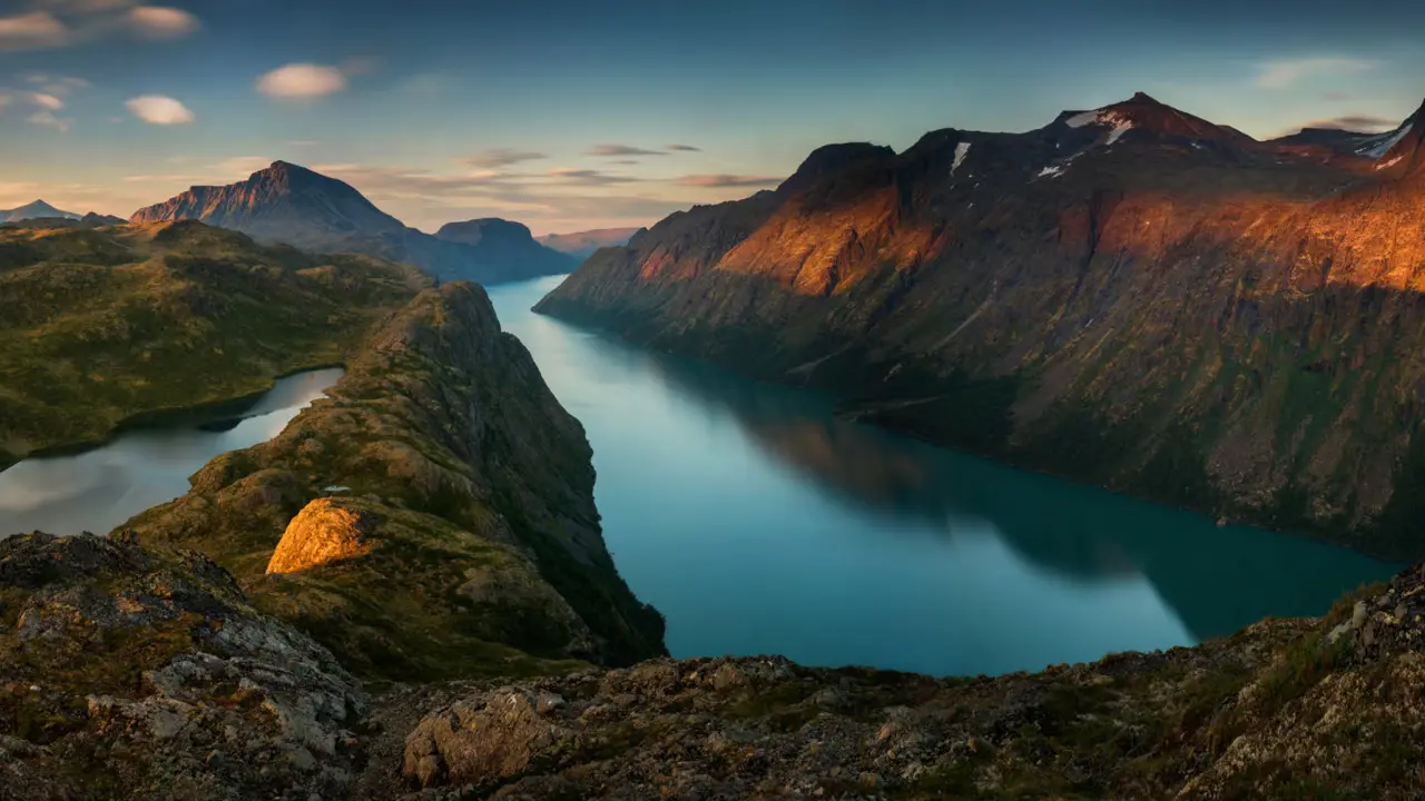 Vakkert bilde av solnedgang over fjell og vann.