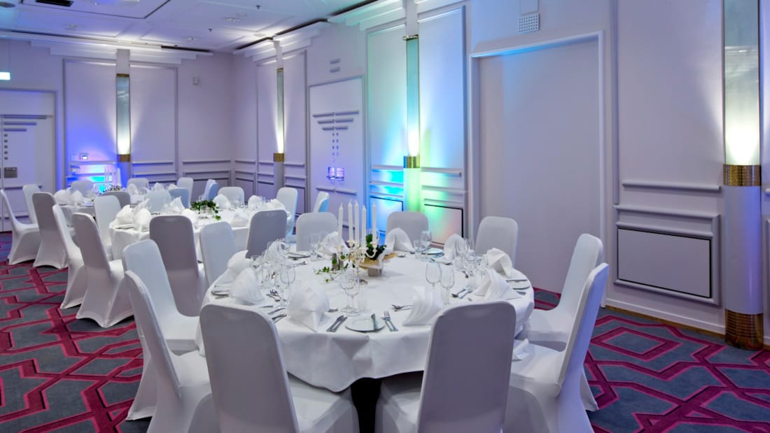 Large venue in a banquet setup with lighting on the walls for events