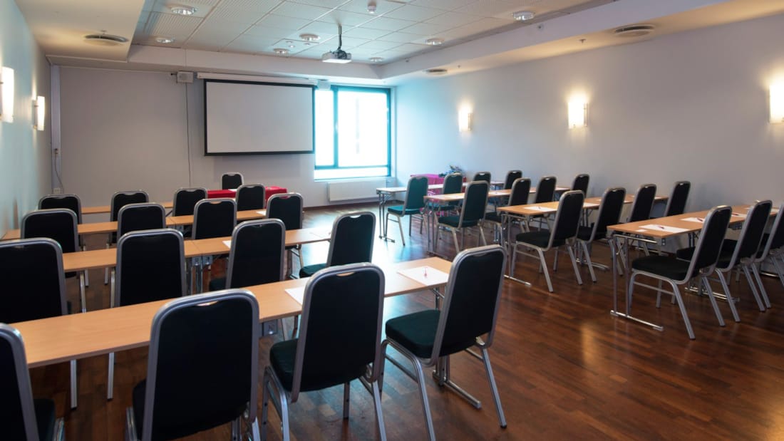 Mødelokale med klasseværelse-opsætning med projektor og dagslys