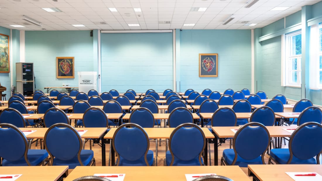 Konferencelokalet Olav bestående af rækker med blå stole og borde i et lyst blåt, moderne konferencelokale