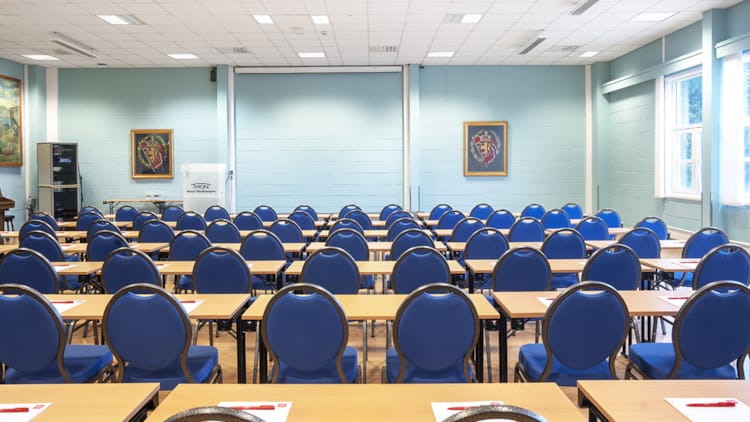 Stor konferencelokale med klasseværelsesopsætning med projektor