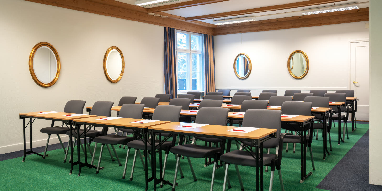 Skeikampen møterom hvitt rom med rader med mørke stoler og lyse bord og grønt gulv
