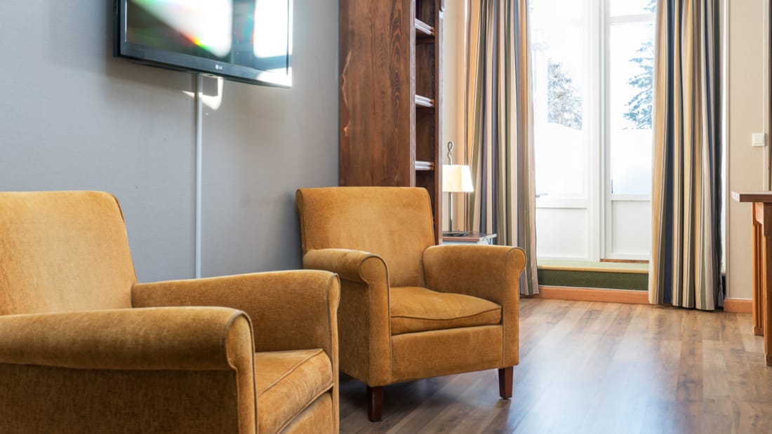 Téléviseur, deux fauteuils et porte de patio avec de grandes baies dans une chambre Business de Thon Hotel Skeikampen