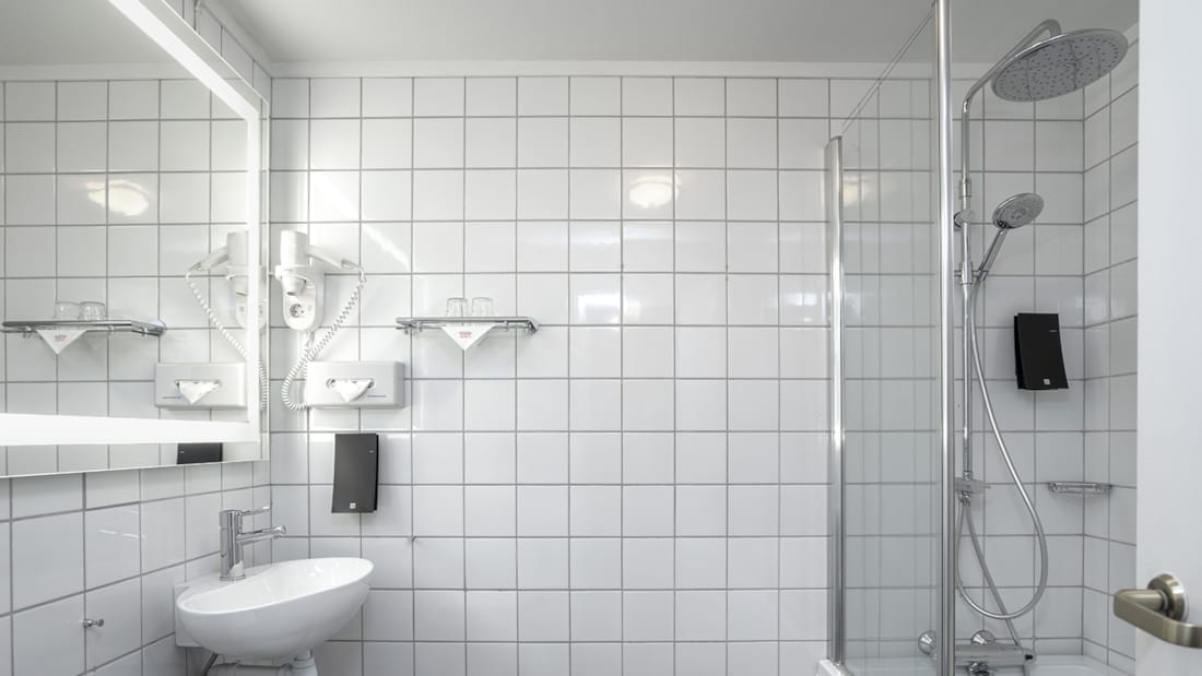 Salle de bains avec grand miroir, douche et baignoire, WC et lavabo dans une chambre familiale et une chambre Business de Thon Hotel Skeikampen