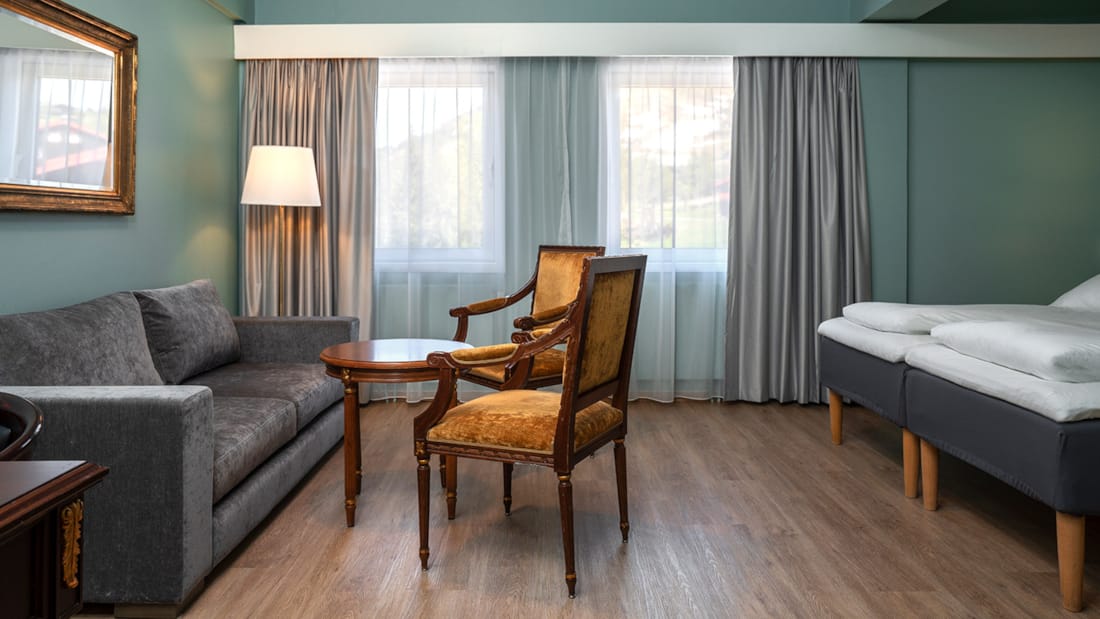 Bed, writing desk, TV and seating area at Thon Hotel Skeikampen