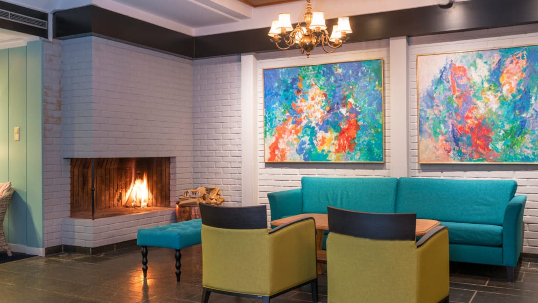 Lobby with seating area in fresh colours, fireplace and artwork on the walls of Thon Hotel Skeikampen