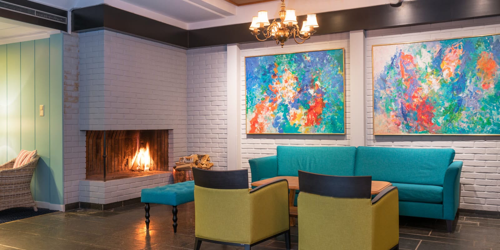 Lobby with seating area in fresh colours, fireplace and artwork on the walls of Thon Hotel Skeikampen