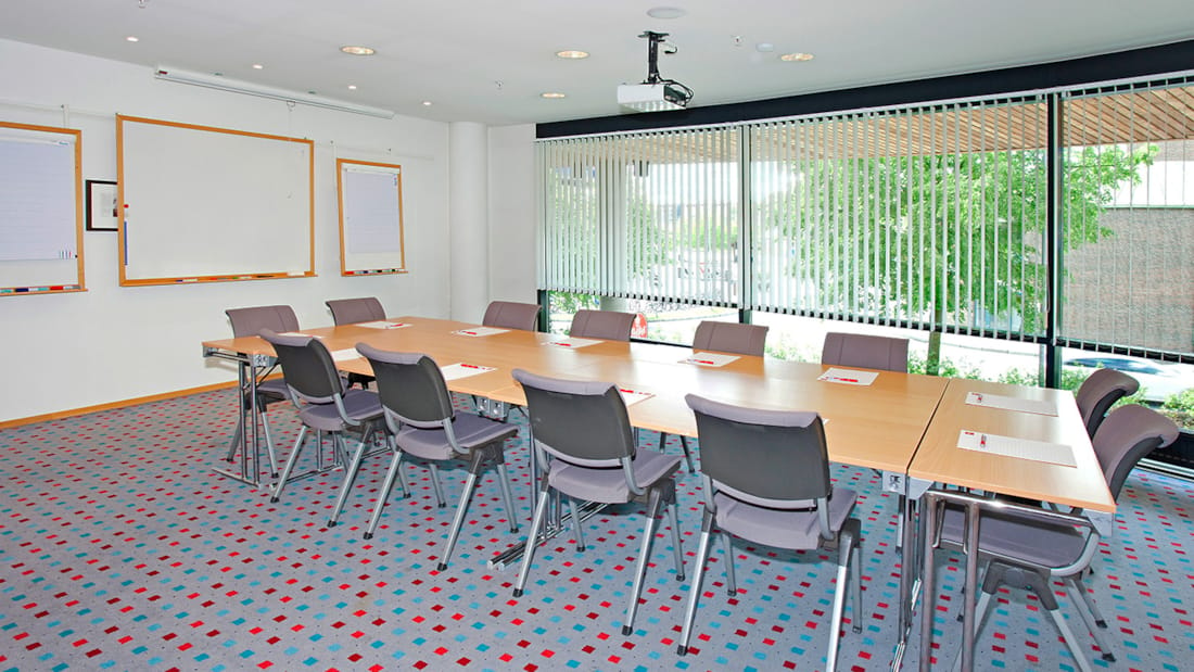 Salle de réunion avec table de contrôle, tableau blanc et projecteur