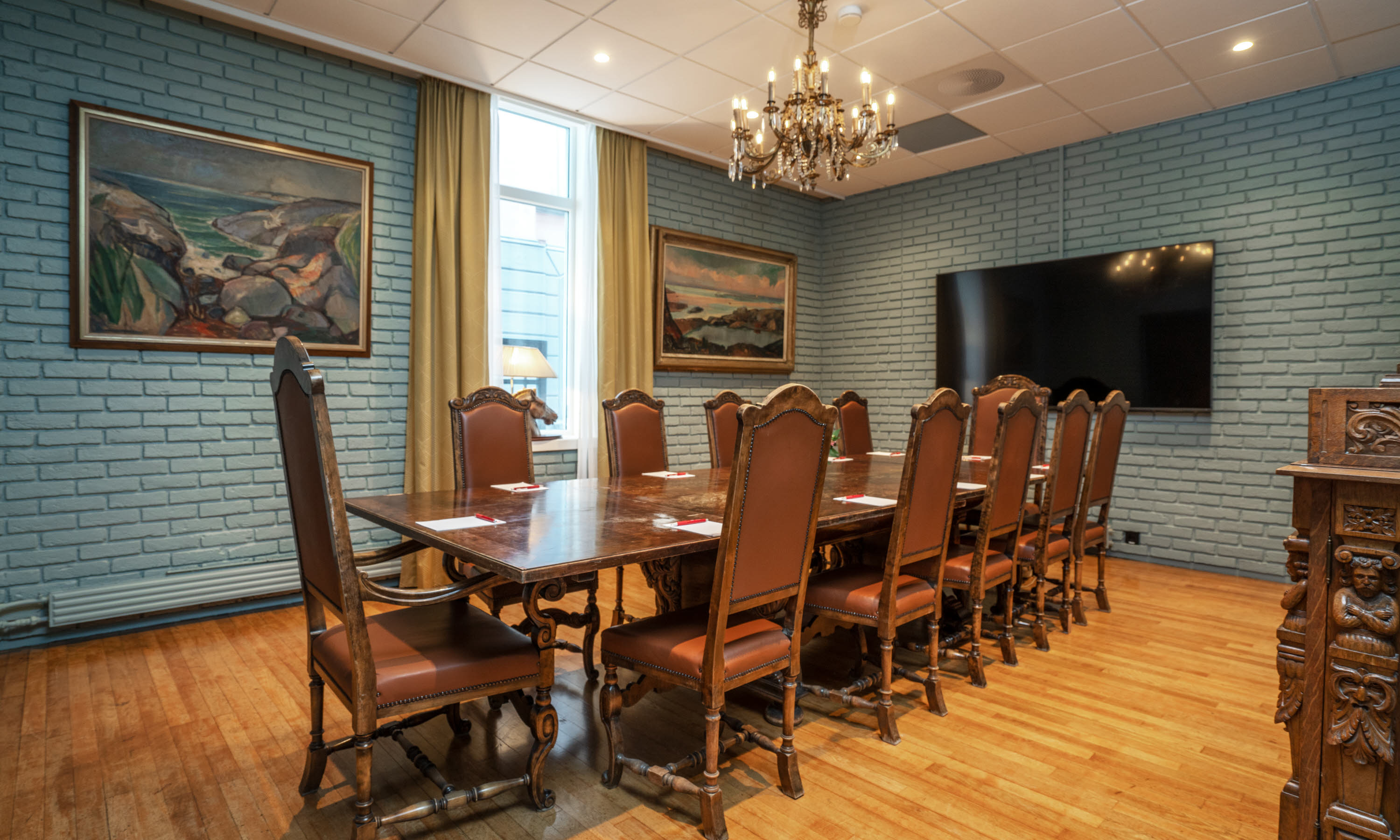 Vergaderruimte met bedieningstafel en tv aan de muur