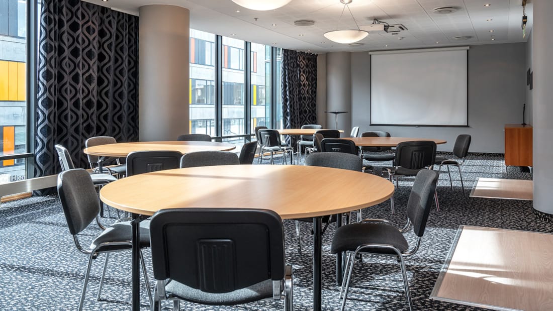 Mötesrum med flera runda mötesbord och tillhörande stolar på Stavanger Forum Hotel