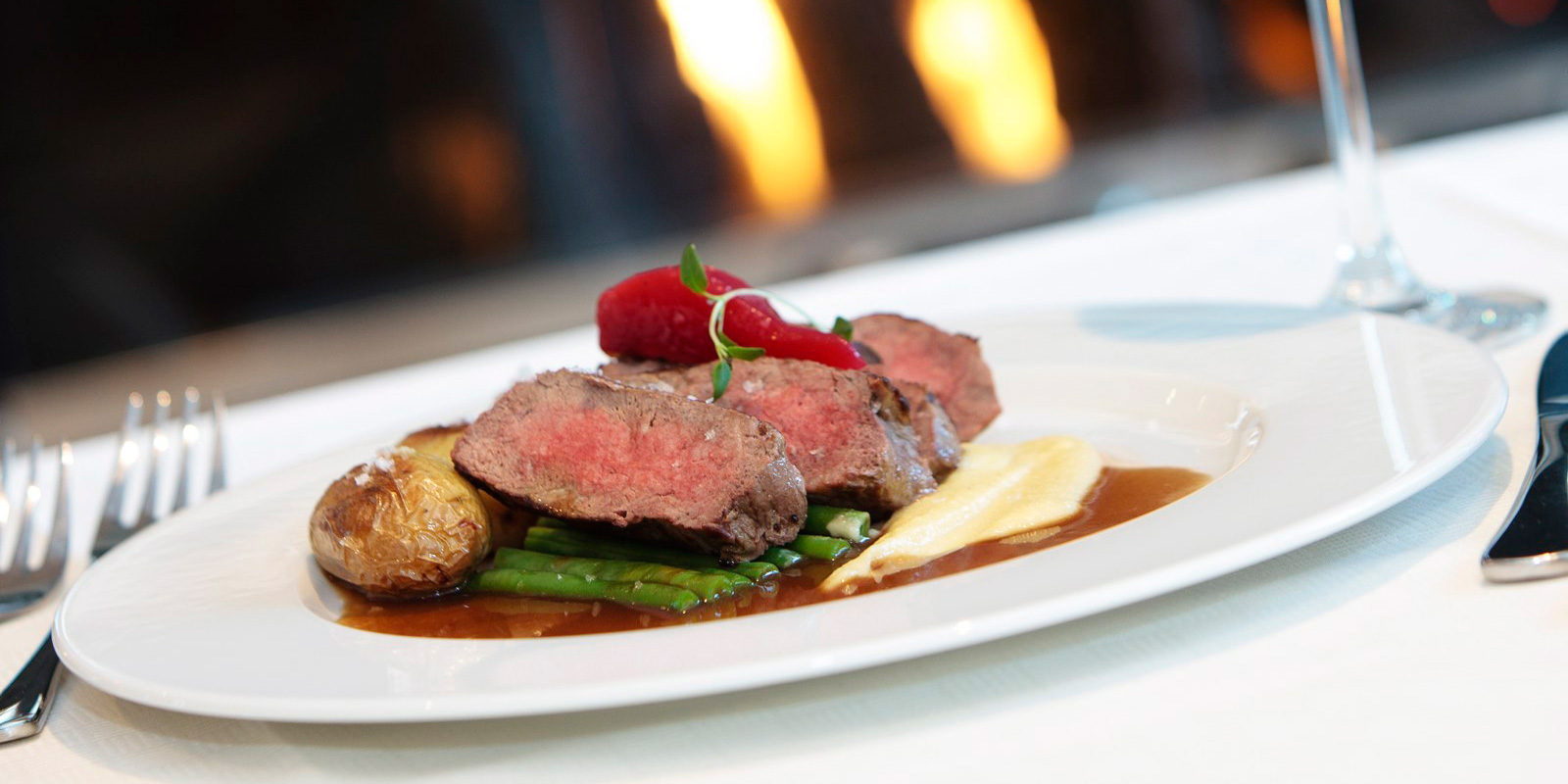 Plate met rundvlees, aardappels, asperges en saus.