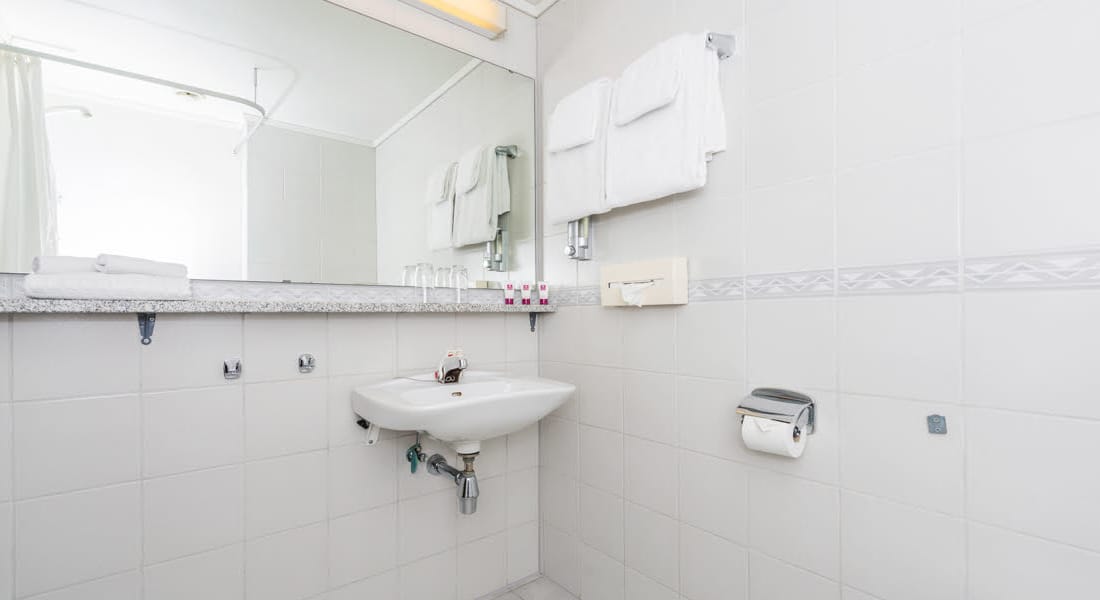 Badeværelse med stort spejl og håndvask i budgetværelse på Hotel Surnadal