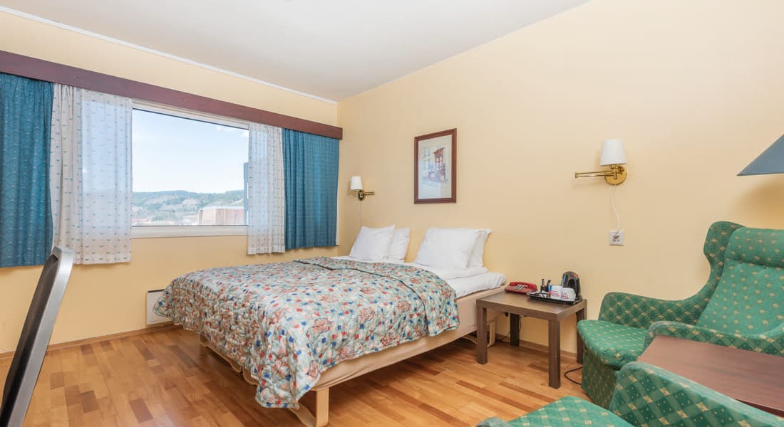 Budgetværelse med dobbeltseng og sengetæppe, skrivebord, to lænestole, garderobeskab på Hotel Surnadal