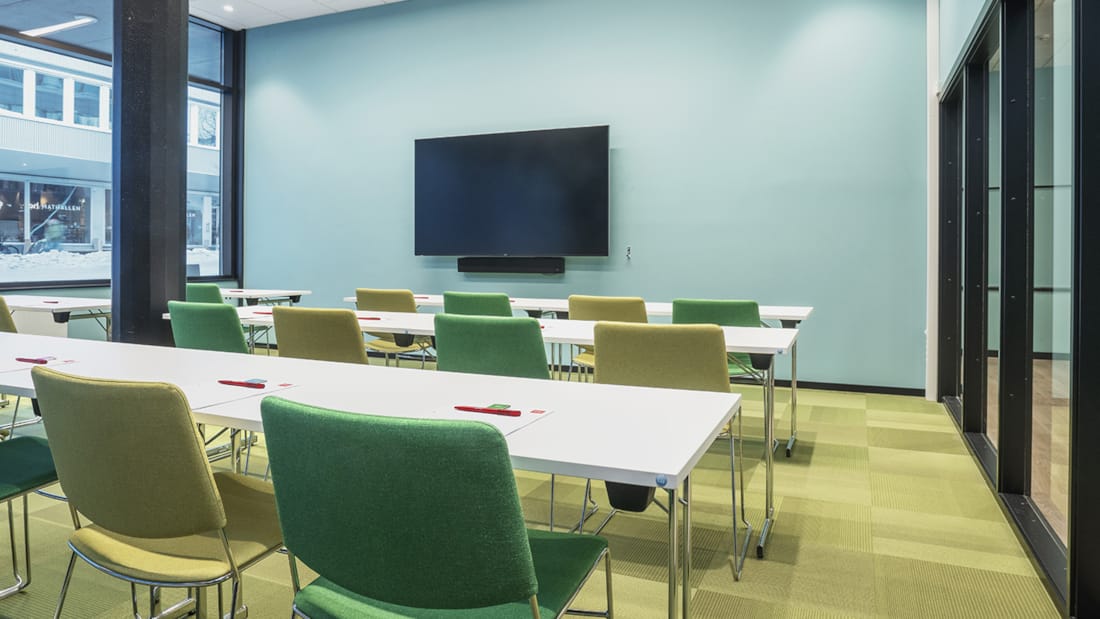 Mødelokale med klasseværelsesopsætning med væghængt tv