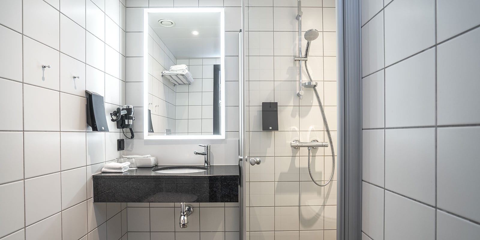 Dusch och handfat i badrummet i våra standardrum på Thon Hotel Tromsø