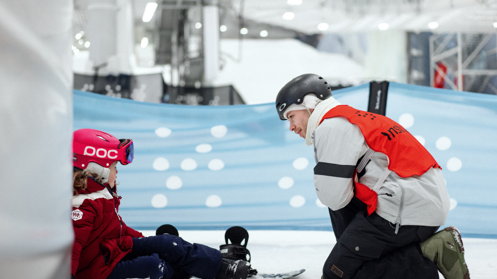 Children in skiing gear and adult man with vest in ski resort