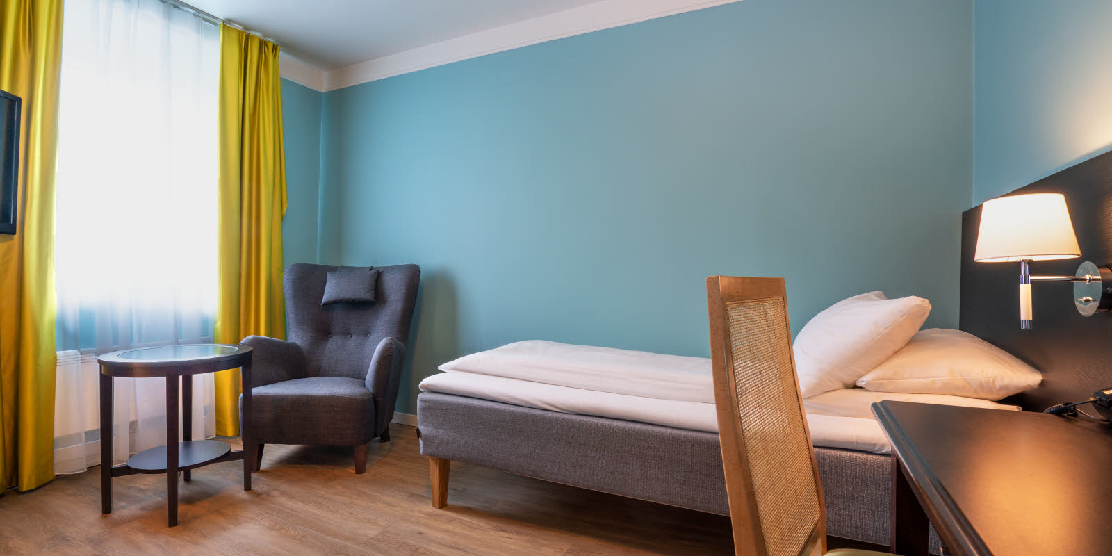 Bed en zithoek in standaard eenpersoonskamer van Thon Hotel Linne Apartments