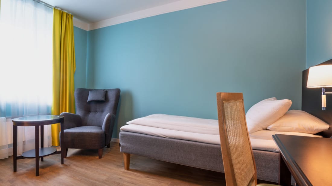 Bed en zithoek in standaard eenpersoonskamer van Thon Hotel Linne Apartments