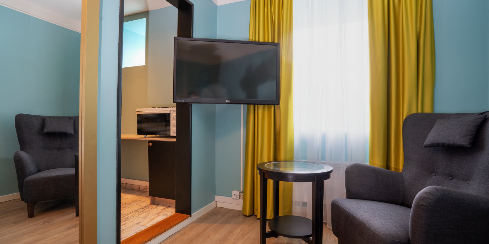 Tv en zithoek in standaard eenpersoonskamer van Thon Hotel Linne Apartments