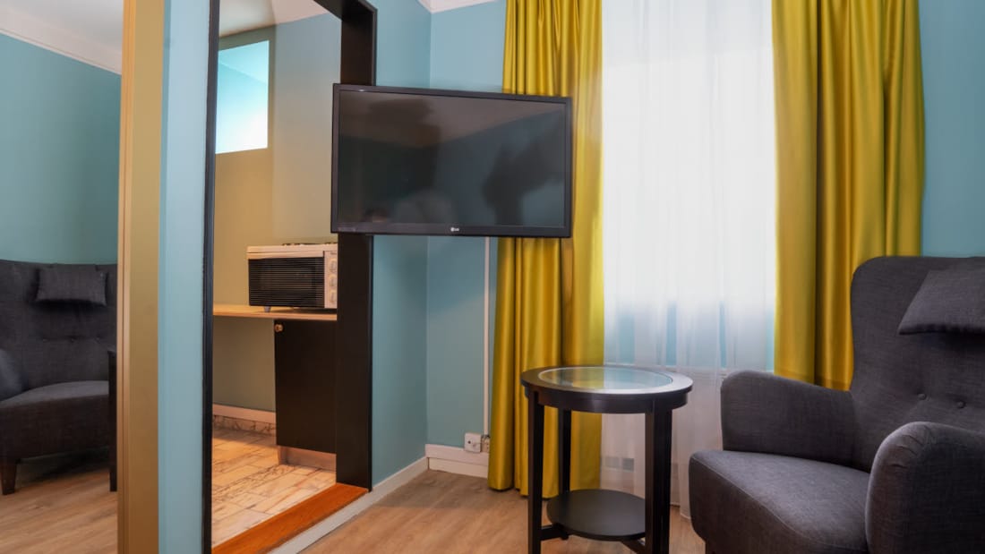 Tv en zithoek in standaard eenpersoonskamer van Thon Hotel Linne Apartments