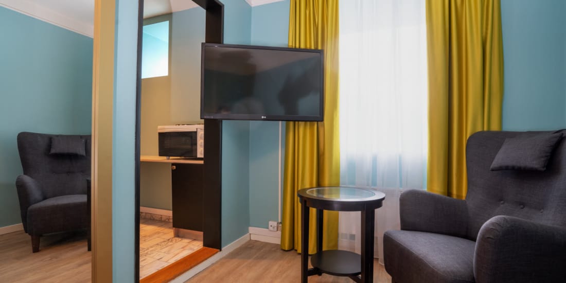 Tv en zithoek in standaard eenpersoonskamer van Thon Hotel Linne Apartments