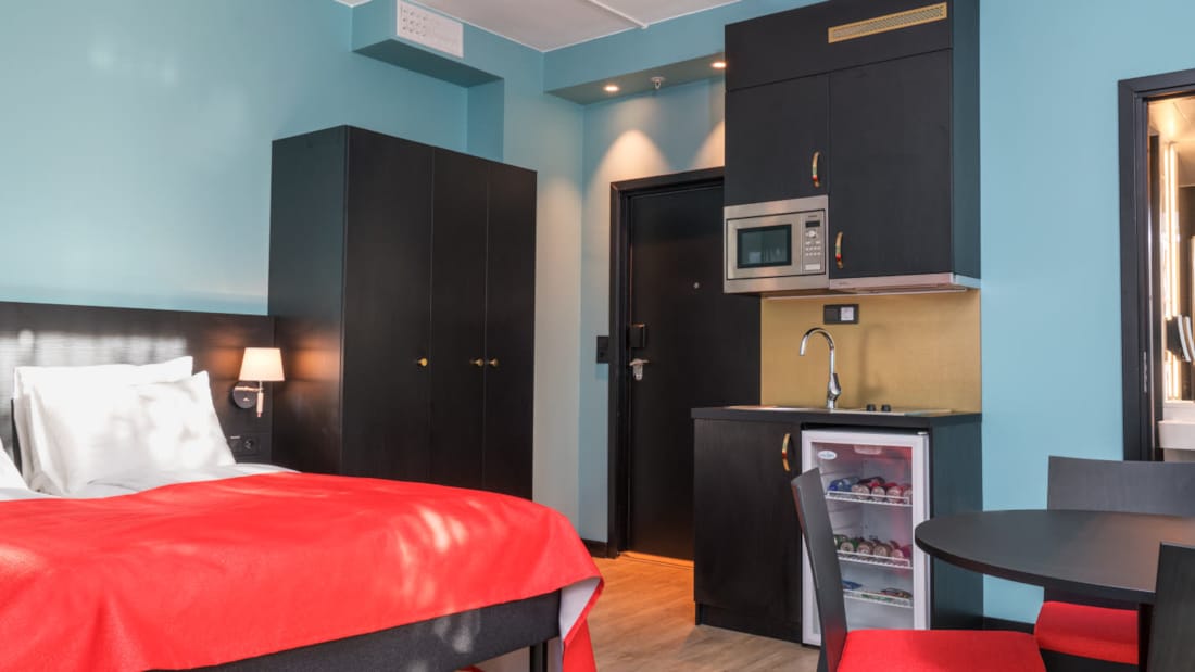 Dubbelsäng, skåp, minikök och köksbord i tvårumslägenhet på Thon Hotel Linne Apartments 