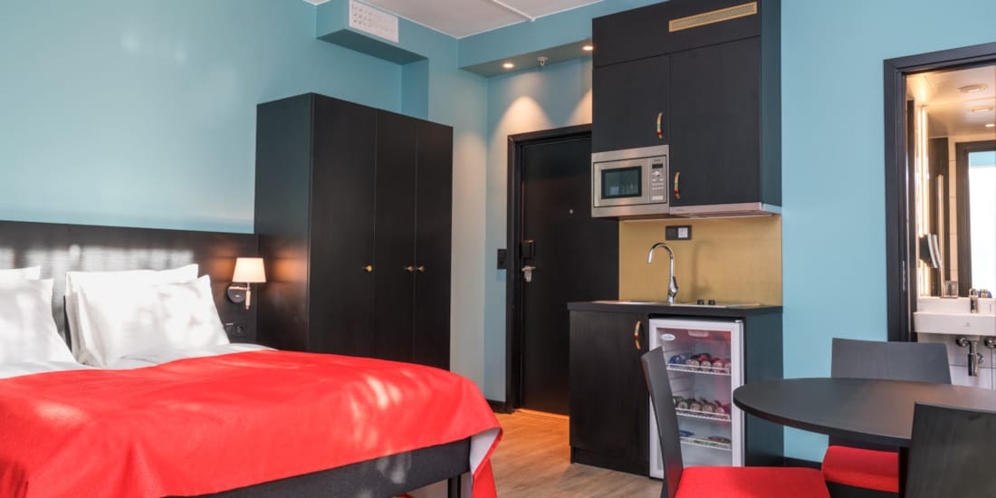 Lit double, armoire, minicuisine et table de cuisine dans un appartement de deux chambres de Thon Hotel Linne Apartments