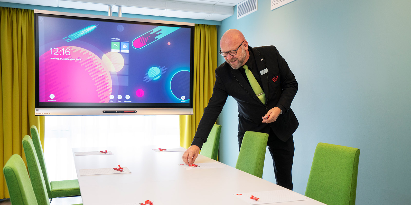 Hotellansatt som forbereder møterom ved å legge frem penn og papir på møterom