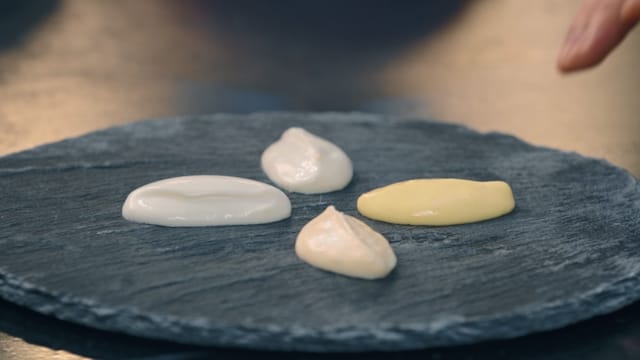 Four different types of mayonnaise on a stone chopping board
