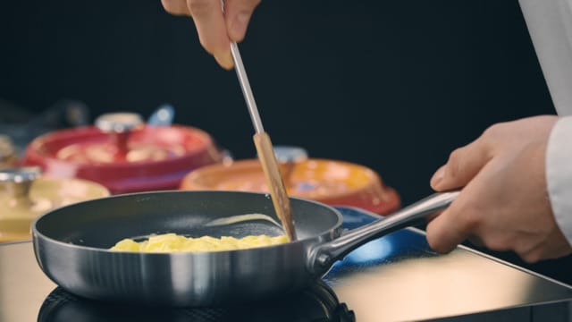 A chef frying an omelette in a frying pan