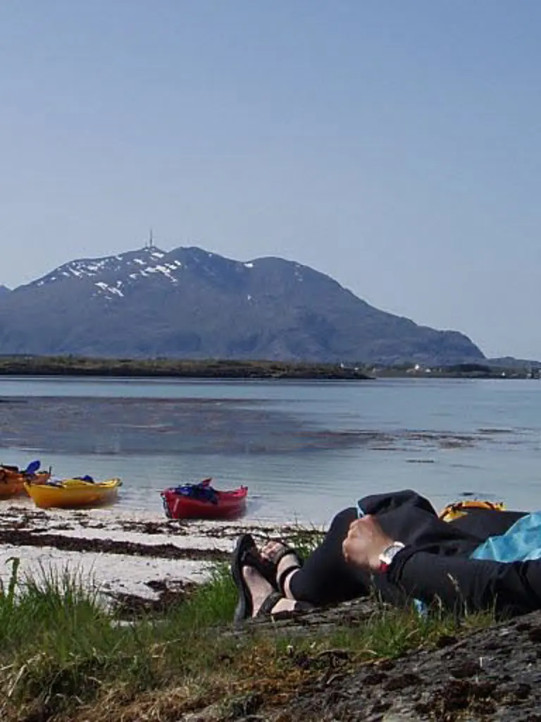 Iemand ligt op het strand met een kajak in Brønnøysund