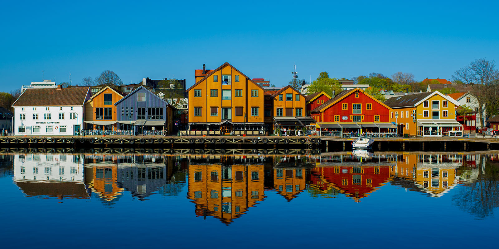 Tønsberg brygge som speiler seg i blått vann