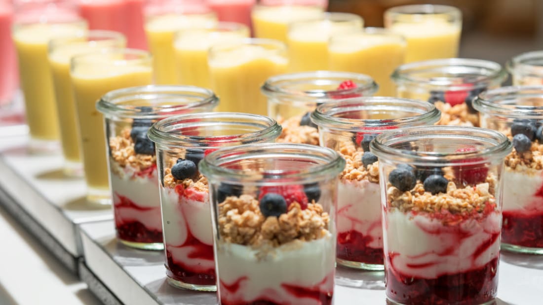 Yoghurt in glass jars, homemade with jam on the bottom, and topped with granola and fresh berries. 