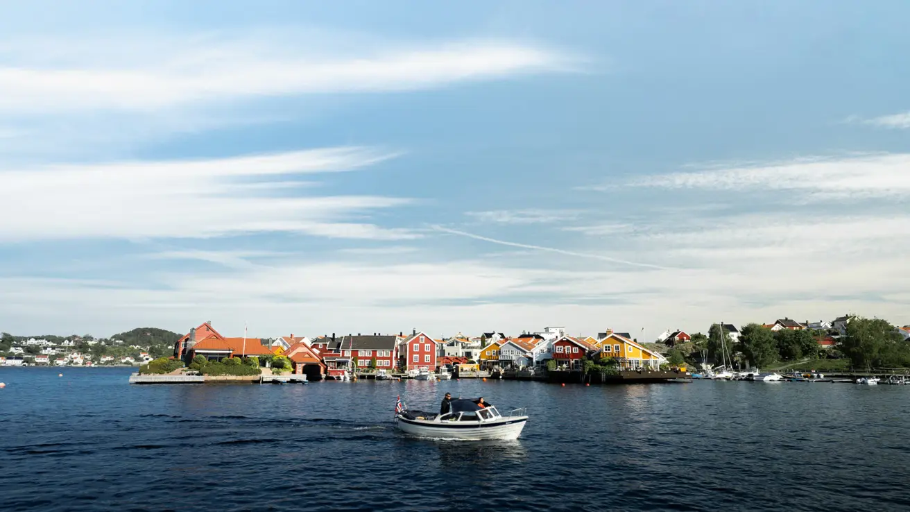 White boat on the water. Buildings in background.