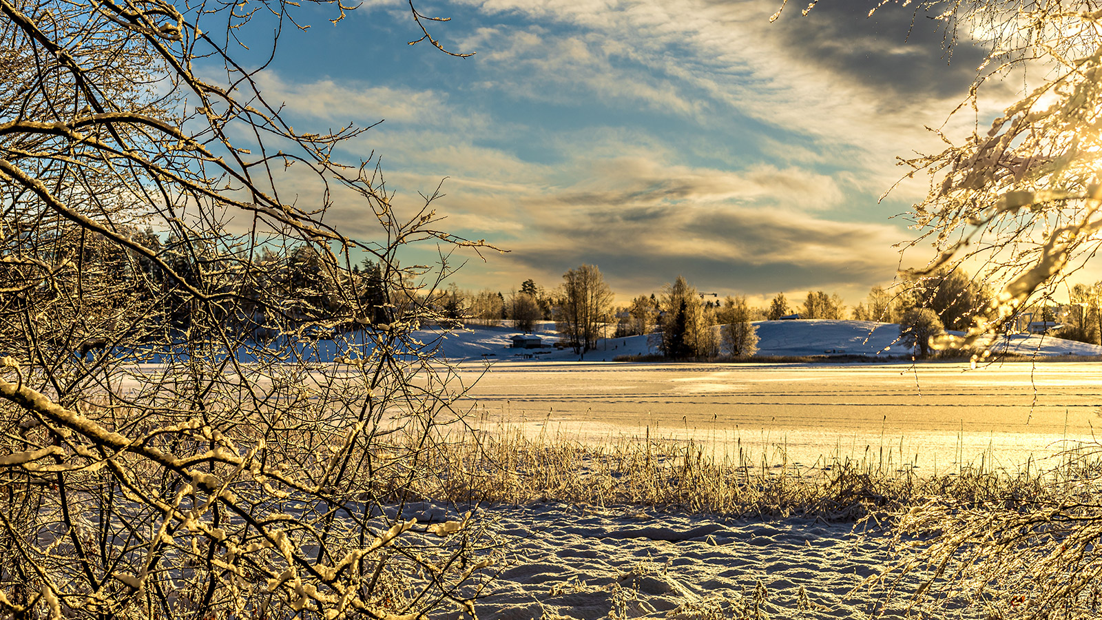 Is- og snøbelagt vann. Blå himmel og sol som skinner i snøen. 