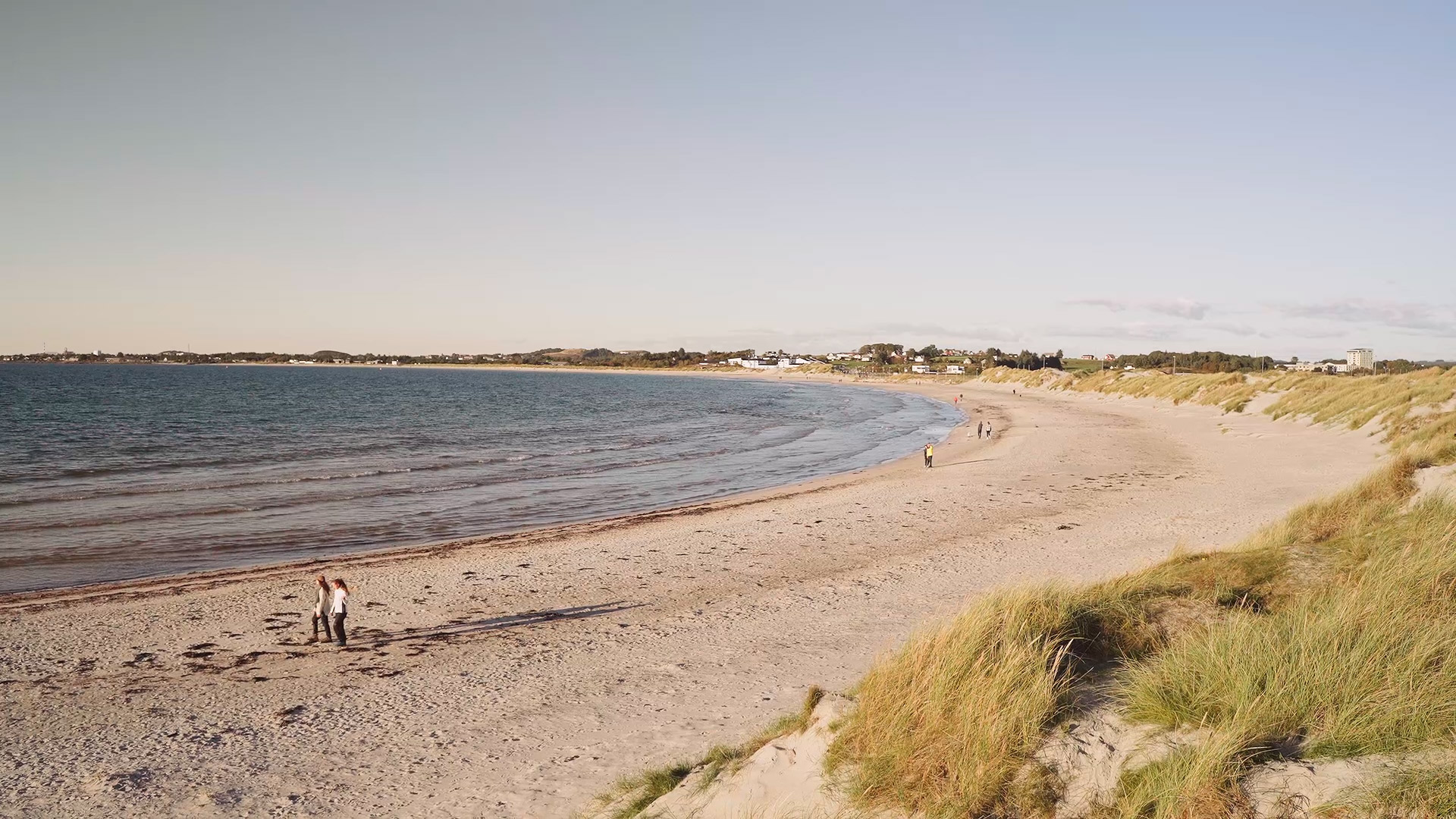Une plage avec des gens qui marchent au bord de l'eau.