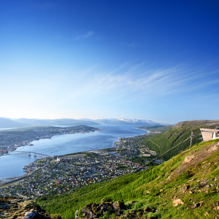 Vue sur la ville de Tromsø depuis le sommet d’une colline. La ville est magnifiquement entourée de montagnes et de mer.