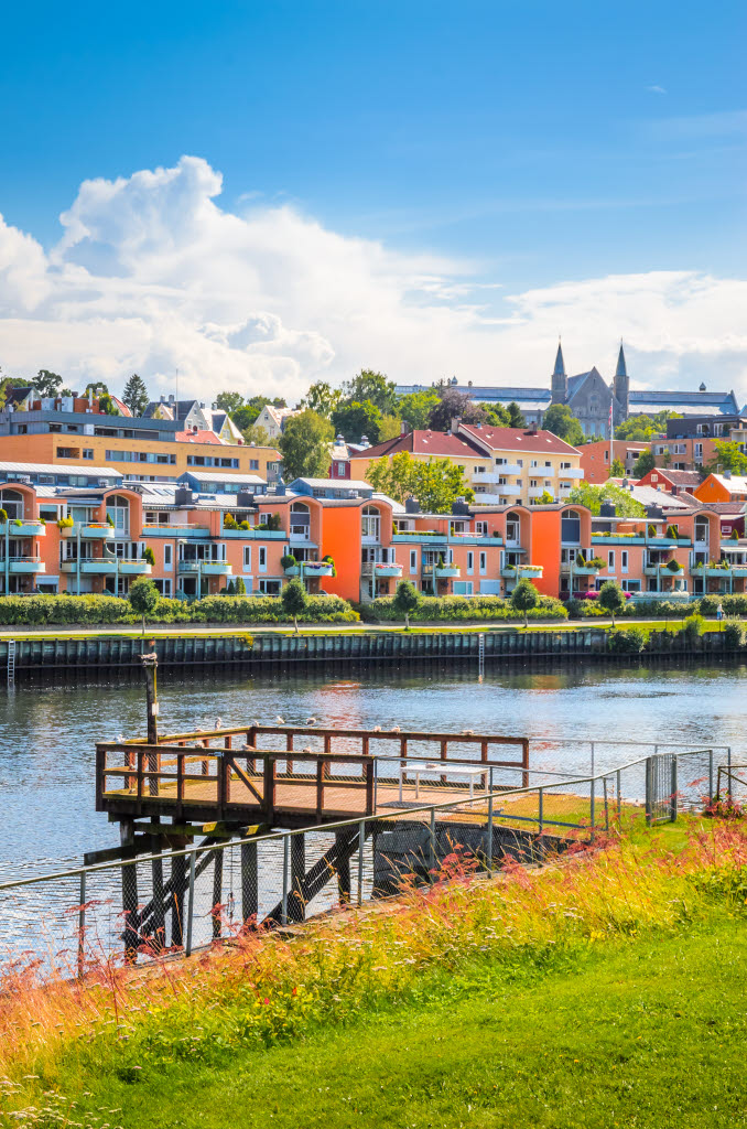 Nidelva and Øvre Bakklandet in Trondheim. Main building of NTNU Gløshaugen in the background. Blue sky with white clouds.