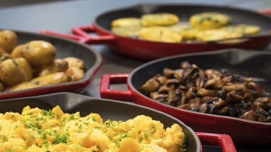Pans with scrambled eggs, mushrooms, and potatoes