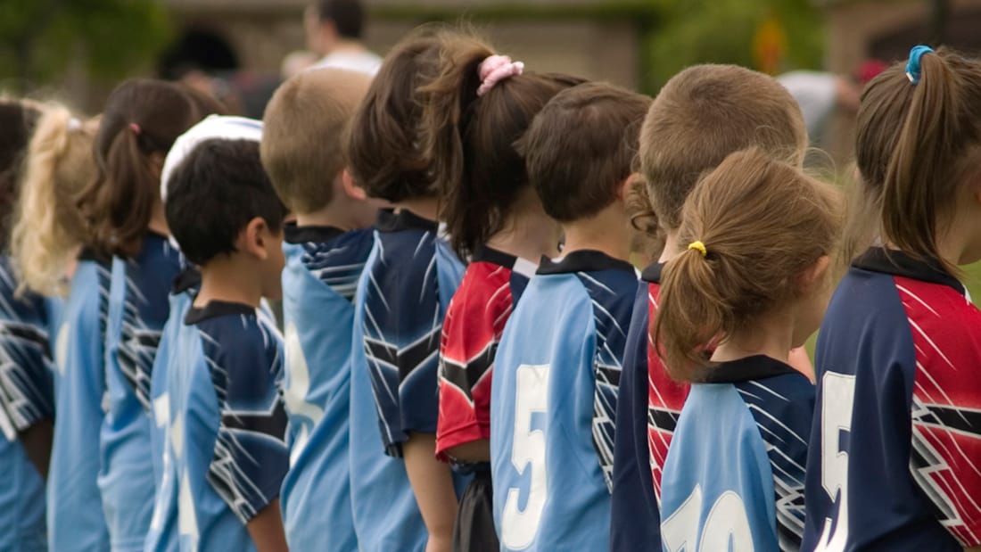 Children in football attire standing in line seen from the side
