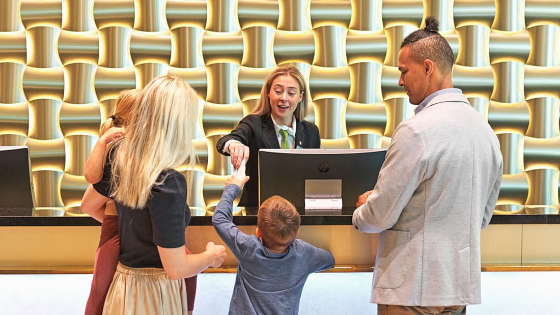 Child communicating with receptionist while family is watching in luxurious lobby