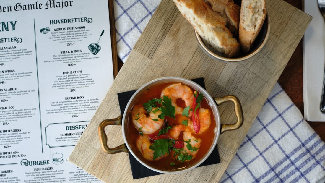 Saucepan with scampi and bread on a board