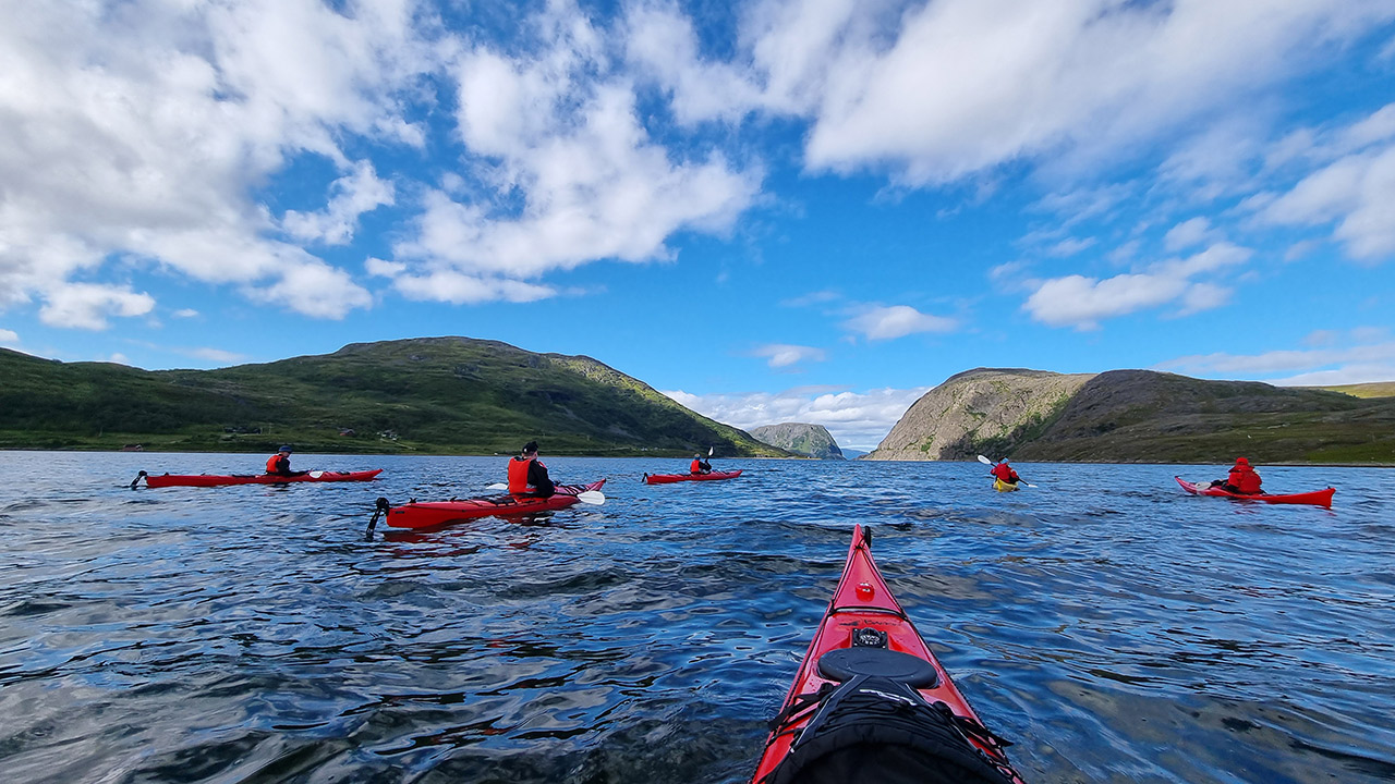 View of water and several kayaks seen from the point of view of a person sitting in a kayak